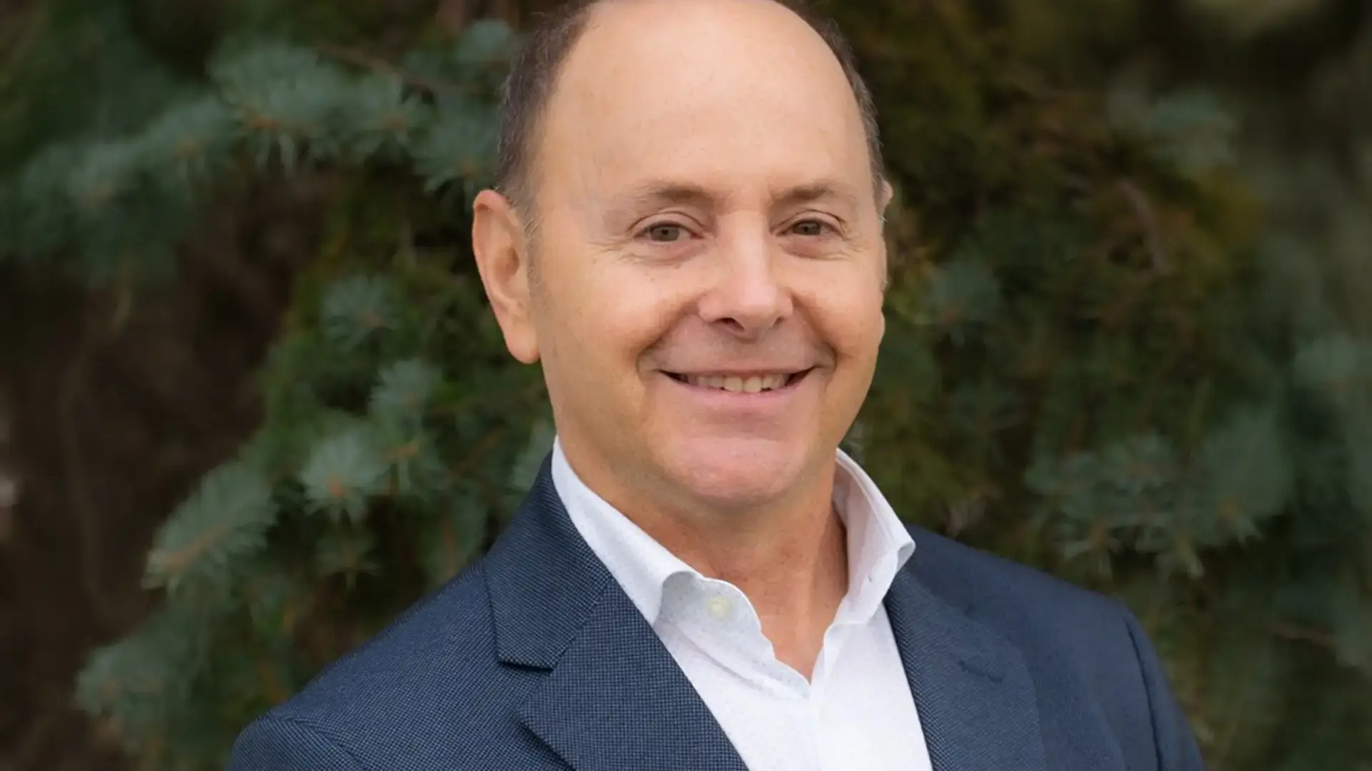 Jordan Berman headshot, in a blue blazer outdoors