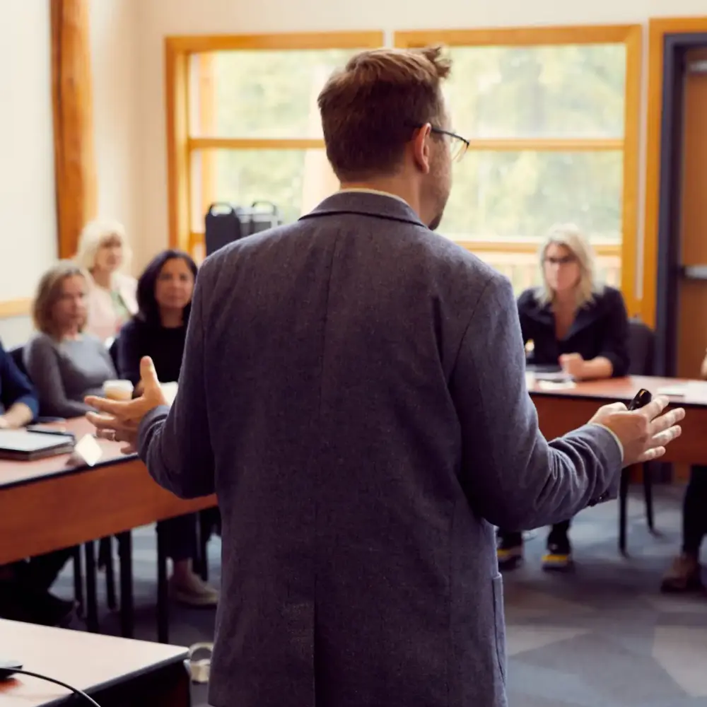 Facilitator seen from behind addressing a seated leadership workshop group