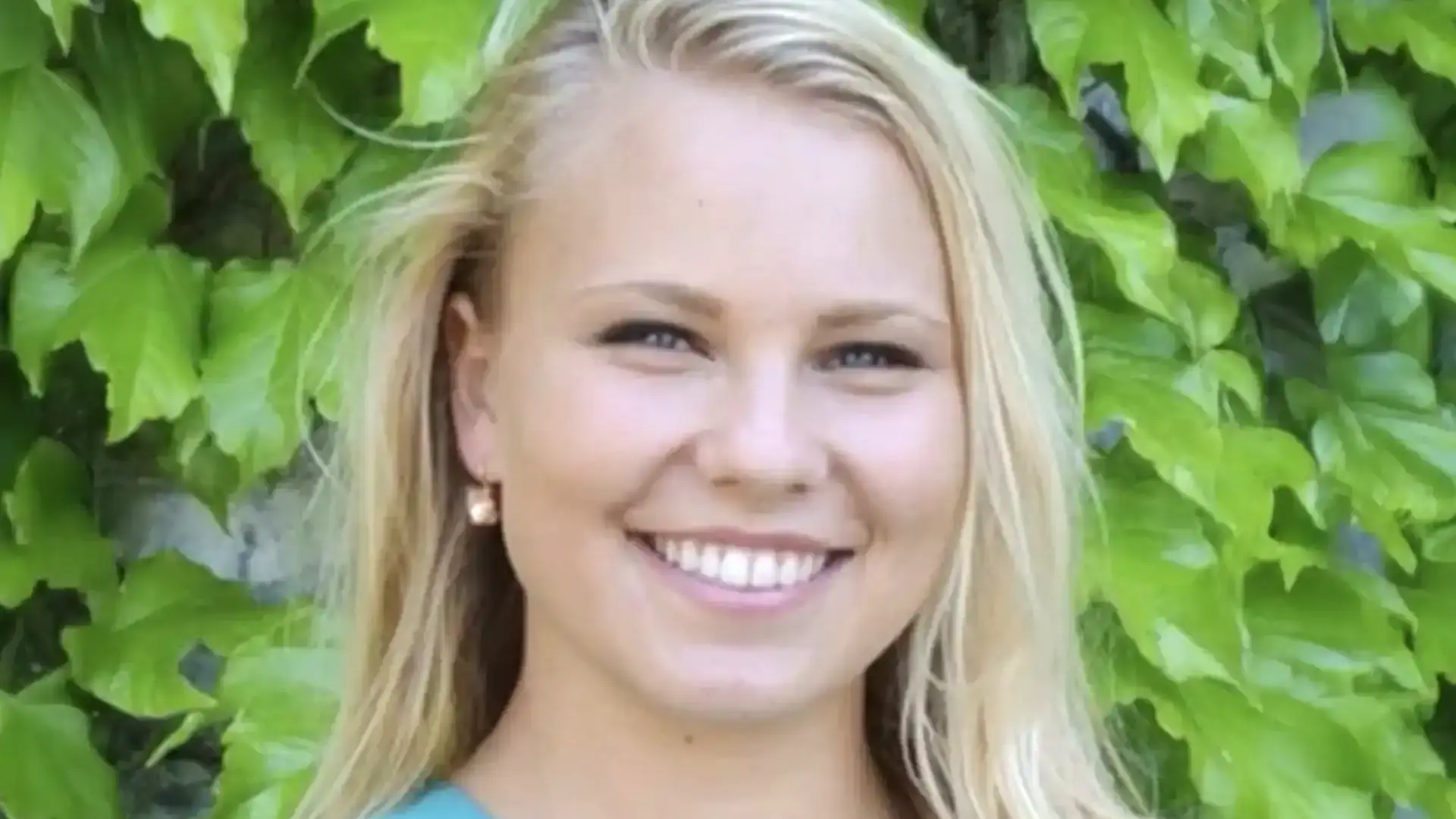 Michelle Woitowich headshot, smiling in front of green ivy