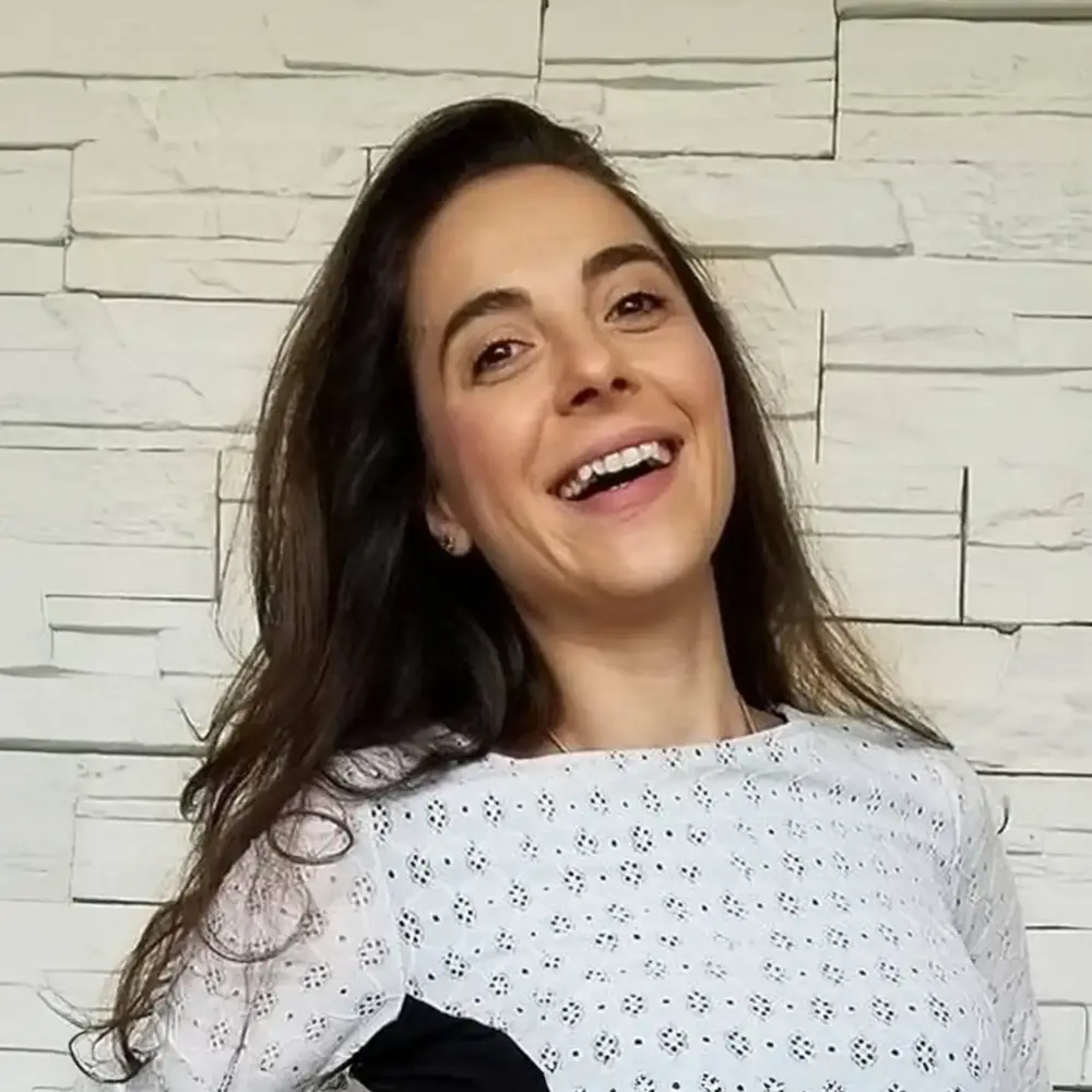 Simona Andonova headshot, laughing against a white brick wall
