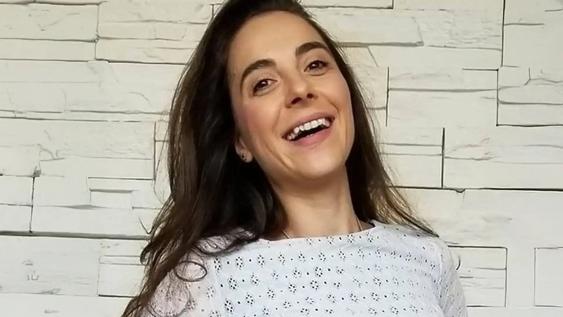 Simona Andonova headshot, laughing against a white brick wall