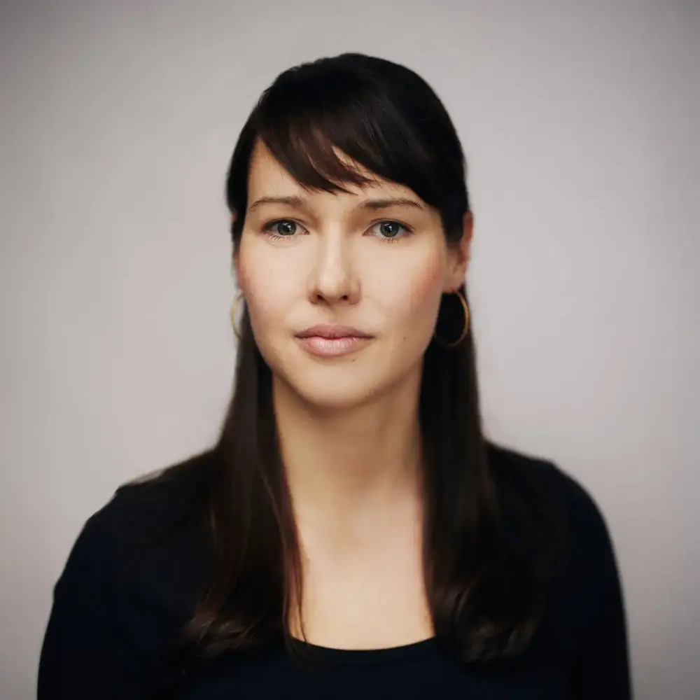Stephanie Damgaard headshot, in black against a neutral backdrop